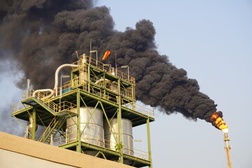 Flare up sends black smoke, flame and pollution into the air at oil refinery plant.