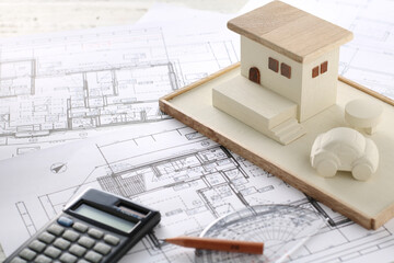 木でできた家の模型とマイホームの設計図のイメージ