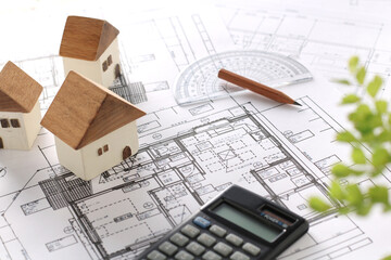 木でできた家の模型とマイホームの設計図のイメージ