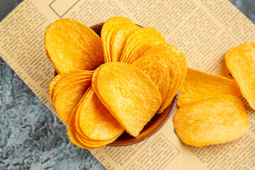 Above view of delicious homemade chips on newspaper on gray background