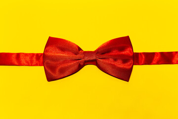 Close-up of red bow tie on yellow background.