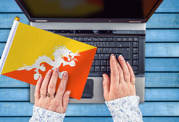 woman hands and flag of Bhutan on computer, laptop keyboard 