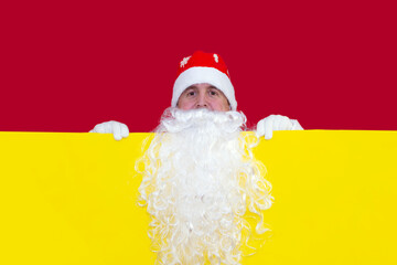 Santa Claus looks out from behind a yellow background.