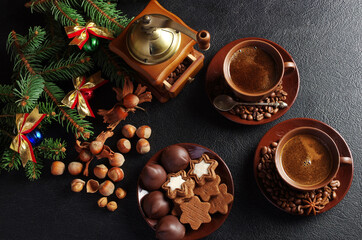 Christmas coffee. Two cups of coffee, a coffee grinder, a saucer with cookies, a decorated spruce branch, hazelnuts on the table.