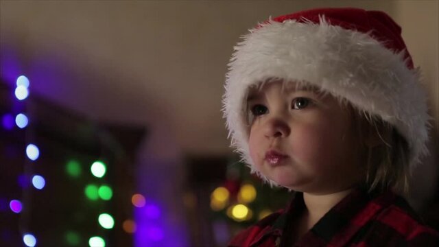 a child in red clothes is sitting waiting for the new year. the concept of celebrating Christmas at midnight. holiday costume