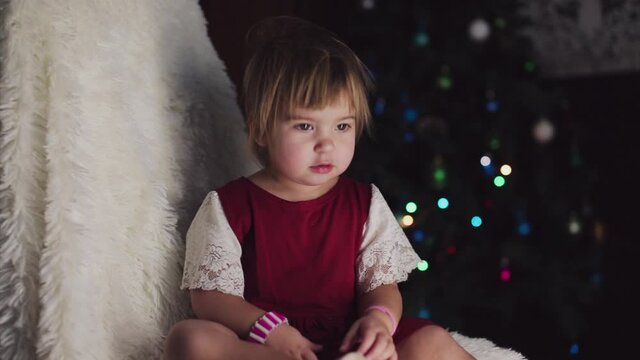 a child in red clothes is sitting waiting for the new year. the concept of celebrating Christmas at midnight. holiday costume. a girl writes a letter to Santa Claus. wish list