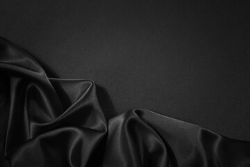 Black silk satin fabric background. Copy space for text or product. Wavy soft folds. Beautiful...