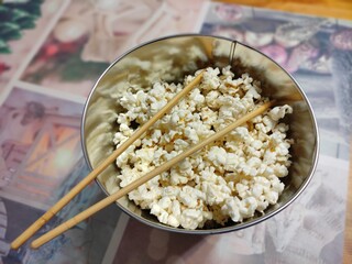 Naklejka premium Ready popcorn in an iron bucket with spiderman on the kitchen table with chopsticks.