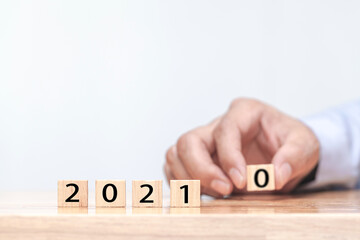 Hand is changing a wooden cube symbolically changes from 2020 to 2021