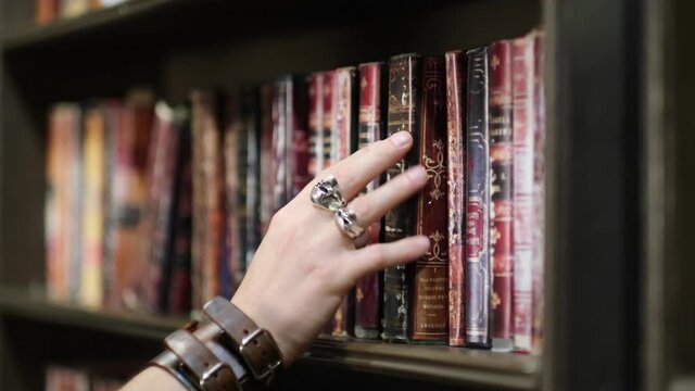 stylishly dressed man chooses a vintage book vintage in an old dark library. close up view. close up view. Slow motion nvideo.