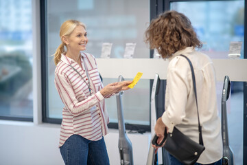 Female sales assistant in striped shirt showing new devices to the customer