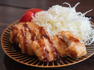 ソースのかかったキチンカツとトマトと千切りキャベツのおかず。