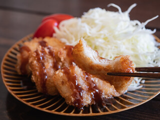 ソースのかかったキチンカツとトマトと千切りキャベツのおかず。
