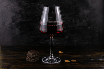 A glass of red wine with almonds and dark chocolate