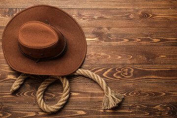 Cowboy hat and rope on wooden background