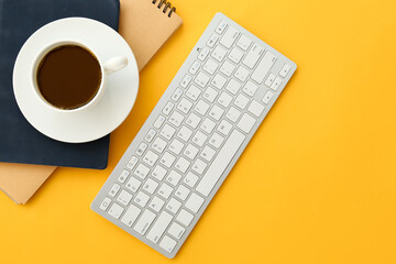 Computer keyboard, cup of coffee and stationery on color background