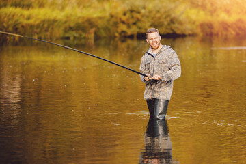 Fisherman using rod fly fishing in mountain river autumn splashing water