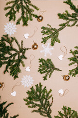 Christmas decorations flat layout with many fir branches, golden ornaments, white wooden hearts on the cardboard background. Eco-friendly christmas ornaments. Scandinavian christmas cards.