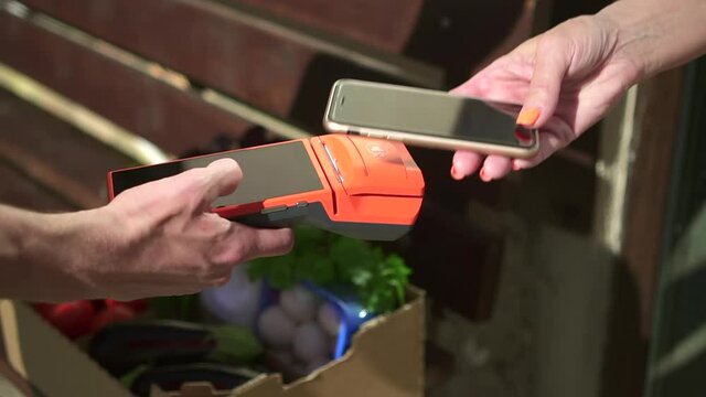 Contactless payment with phone at food delivery Spbd closeup. Woman pay through smartphone during grocery shopping. Courier deliver order and make online bill banking cheque