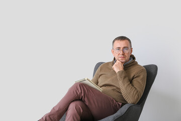 Obraz premium Male psychologist sitting in armchair near light wall