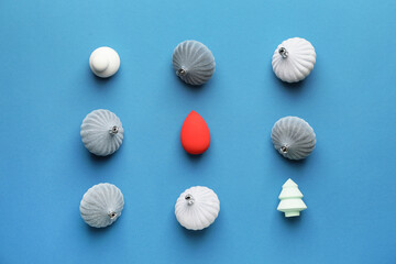 Christmas balls and makeup sponges on color background