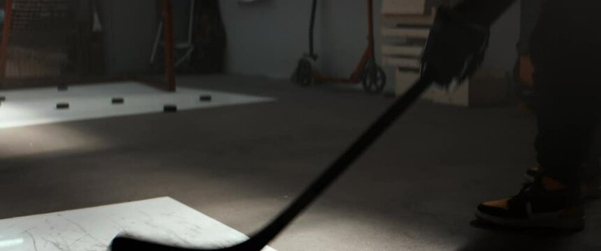 Kid boy hockey player practicing shots inside a covered garage at home. Shot with 2x anamorphic lens