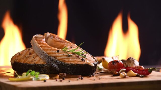 Grilled salmon fish with various vegetables on the flaming grill