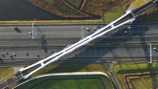 Zandhazenbrug arch bridge over the A1 highway in Muiderberg, The Netherlands Aerial view from above with traffic going under the bridge and a train crossing