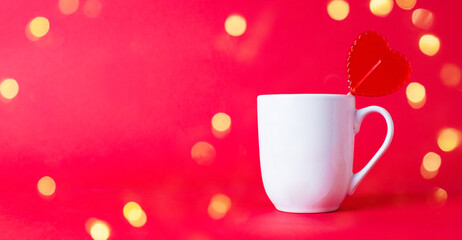Red sweet heart shaped Lollipop in white mug with christmas bokeh
