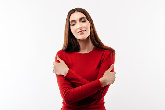 Image of young happy woman hugging herself, wearing in casual red clothes