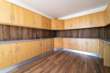 Empty kitchen with dark wooden floating laminate flooring. House interior, wide dinner area or...