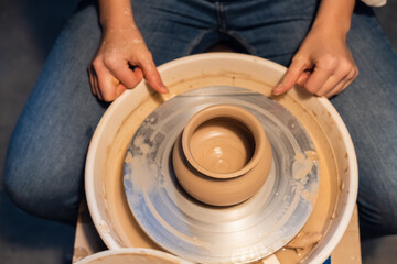 beautiful hands of a young girl potter in the process of sculpting a vase with clay and tools