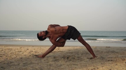 Young flexible man doing yoga outdoors in nature