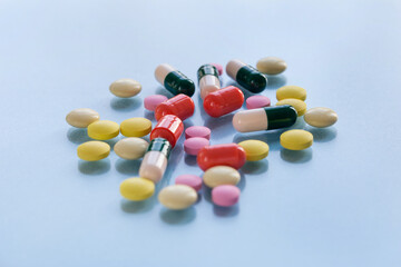 Colorful pills and capsules isolated on a blue background. Medical health or drugs addiction concept.