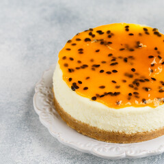 Passion fruit cheesecake on a white plate on a gray concrete background. Delicious homemade cake. Selective focus, copy space