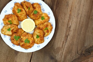 Pork schnitzels served on the plate. Decorated with sliced lemon and parsley. Brown rustic table. Top view, flat lay, copy space.