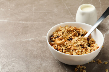 Bowl with granola and milk on gray background