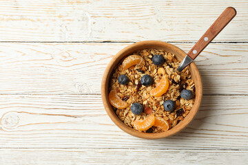 Bowl with granola and spoon on wooden background
