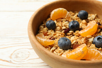 Bowl with granola on wooden background, close up