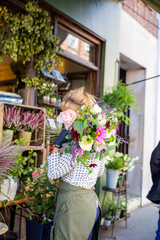 Woman holding and covering her face behind a bouquet of mixed flowers