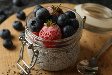 Board with jar of delicious chia pudding on black smokey table