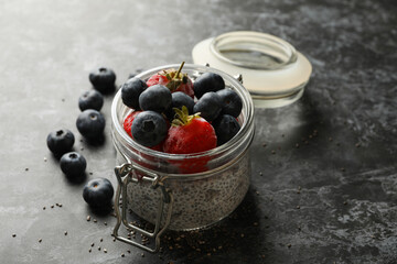Jar with delicious chia pudding on black smokey table