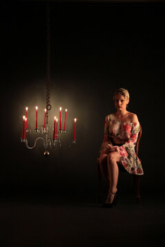 Eine Frau sitzt einsam neben Kerzenlicht im Dunkel der Nacht