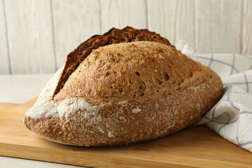 Board with bread and napkin on white table