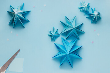 Simple origami 3D Christmas tree made from blue paper. Step by step instruction, step 18. Use different size and color paper to make smaller Christmas tree with steps 2 to 16
