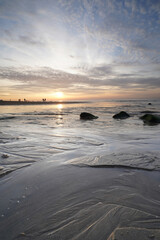 Naklejka premium Sunset on the beach. Seascape with an impressive blue, orange sky. Green rocks in foreground