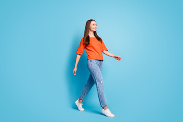 Fototapeta na wymiar Profile full length photo of attractive shiny lady dressed red t-shirt walking looking empty space isolated blue color background