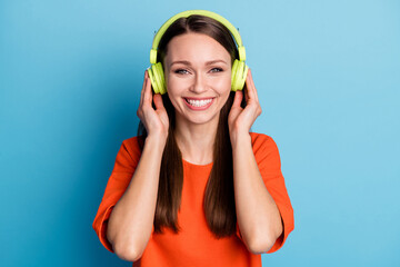 Photo of charming young woman wear casual orange t-shirt listening favorite song arms green headset isolated blue color background