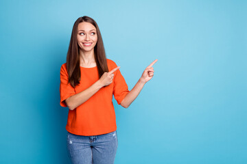 Photo of sweet beaming young lady dressed casual outfit looking pointing two fingers empty space...