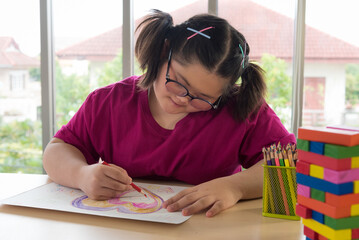 Portrait of Asian disabled child kid complex genetic disorders girl draw a picture with colored pencil